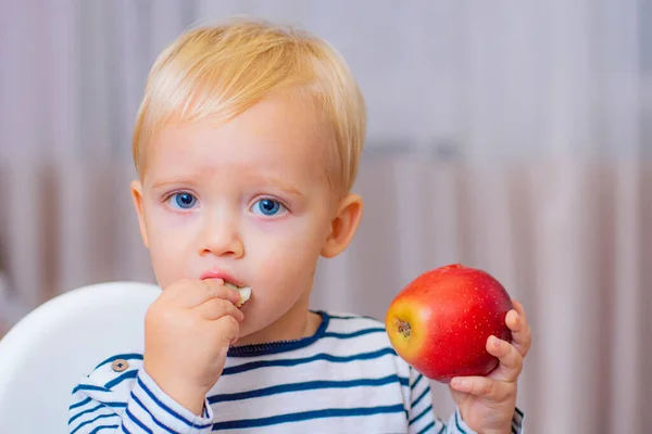 Babyvoeding. Eet gezond. Peuter heeft thuis een snack. Kind eet pap. Jongen leuke jongen blauwe ogen zitten aan tafel met bord en eten. Gezonde voeding. Gezond eten. Jongen schattig baby eten ontbijt — Stockfoto