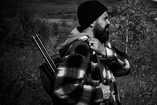 La chasse en montagne. Chasseur avec fusil de chasse en chasse. Chasseur barbu tenant une arme et marchant dans la forêt. — Photo
