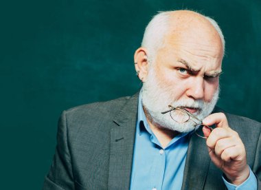 Tebeşir tahtası kopyalama alanı. Yaşlı sakallı olgun öğretmen. Öğretmen yetenekli bir lider. Öğretmenler meydan okuyor ve ilham veriyor. Öğretmenlik işi - meslek ve öğrenme konsepti. Eğitim.