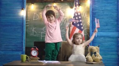 Bağımsızlık Günü tatili. Amerikalı çocuklar bağımsızlık gününü kutluyor. Amerikan bayrağı. Vatanseverlik kavramı. 4 Temmuz. Mutlu çocuklar. Okulda bayraklı Amerikalı çocuk.