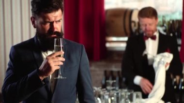 Barmen barda çalışıyor. Yakışıklı zarif iş adamı barda bir bardak şampanya tutuyor..