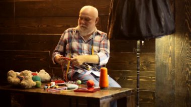 Terzi kıdemli adam. Yaşlı adam evde oturmuş, dikiş iğneleri ve yün iplikler örüyor. Emeklilik yaşı.