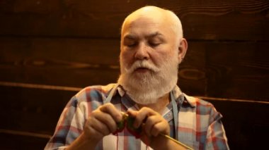 Örgü ören ellerin yakın çekimi. Terzi kıdemli adam. Ahşap çift uçlu iğneli farklı renklerde yün ipliği..