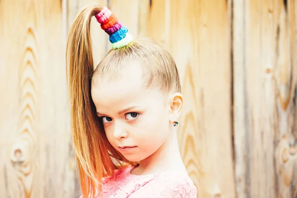 Portret van een vrolijk meisje, kijkend naar een camera geïsoleerd over een houten achtergrond. Mooi jong meisje met een sprekende blik. Schattig model is genieten van fotoshoot in de studio. Gelukkig kind. — Stockfoto