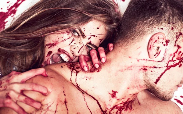 Krwawa para, wampirza dziewczyna gryzie muskularnego mężczyznę w szyję. Okropny odcinek Halloween, dziewczyna gryzie swojego chłopaka w szyję, z krwią na twarzy i żądzą krwi. — Zdjęcie stockowe