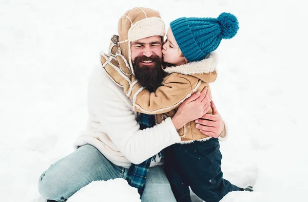 Táta a kluk se usmívají a objímají. Užívám si zimu přírody. Roztomilý malý chlapec a šťastný otec na zasněženém poli venku. — Stock fotografie