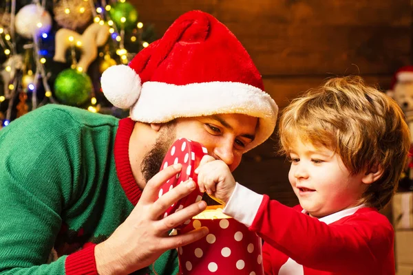 As crianças desfrutam das férias de Natal. Criança feliz com presente de Natal. Desejo-lhe um feliz Natal. Feliz pai e filho em chapéu de Papai Noel com presente ter um Natal. — Fotografia de Stock