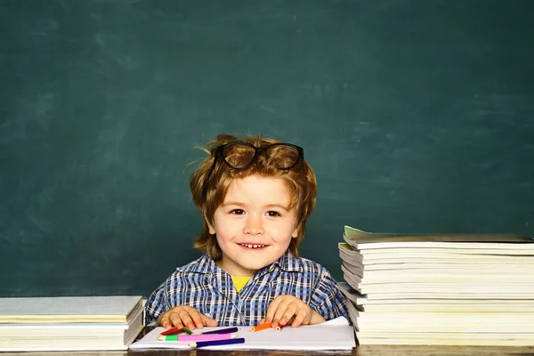 Küçük komik çocuk tahtayı işaret ediyor. Küçük öğrenci mükemmel bir notla mutlu. Sınıf odası. Çocuk okulu. Okul çocuğu. — Stok fotoğraf