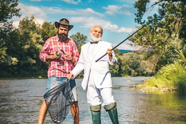 Generazioni età: nonno e padre. Nonno e ragazzo pescano insieme. Buon nonno e nipote con canne da pesca sull'ormeggio del fiume. — Foto Stock