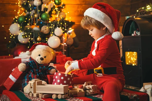 Αστείο παιδί που κρατάει Χριστουγεννιάτικο δώρο. Χαριτωμένο παιδάκι κοντά στο χριστουγεννιάτικο δέντρο. Χειμερινά Χριστούγεννα. Πρωτοχρονιά Χριστούγεννα έννοια. — Φωτογραφία Αρχείου