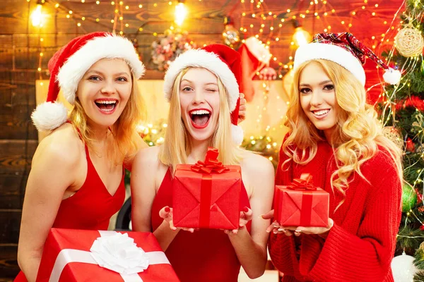 Meninas de Natal bonitas com cabelo loiro e lábios vermelhos está segurando uma caixa de presente. Belos estudantes felizes do sexo feminino com caixa de presente na festa de celebração. — Fotografia de Stock