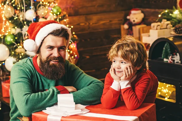 겨울 옷을 입은 아버지와 함께 행복 한 어린 아들 크리스마스 트리 근처 산타를 생각 합니다. 크리스마스 가족. 나무로 된 집에서 크리스마스 선물을 하고 있는 아버지 와아들. — 스톡 사진