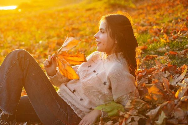 Femme profiter de l'automne. Fille détendue étendu feuilles tombées sur jour ensoleillé d'automne. Chaleur et convivialité. Fond de feuilles d'automne femelle. Attrapant rayons de soleil du soir — Photo