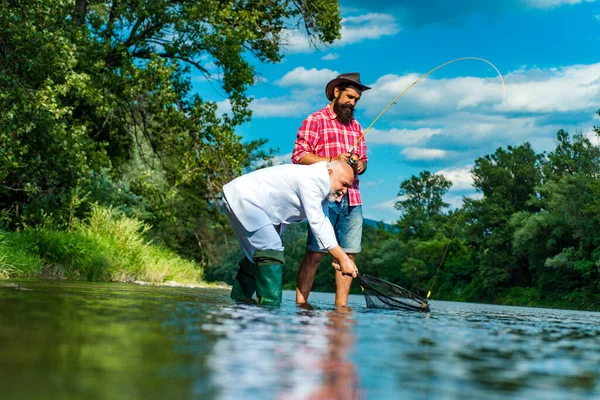 Homem maduro com amigo pesca. Pesca como férias. Descanso e recreação. Continua a pescar. Homens barbudos a pescar peixe. Pessoas felizes e alegres. Estou reformado. Lazer. Pescadores felizes. — Fotografia de Stock