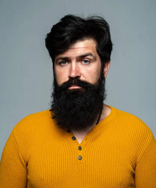 Peluquero con barba larga y bigote en barbería. Hombre barbudo. Guapo joven macho chico en gris fondo mirando a la cámara. —  Fotos de Stock