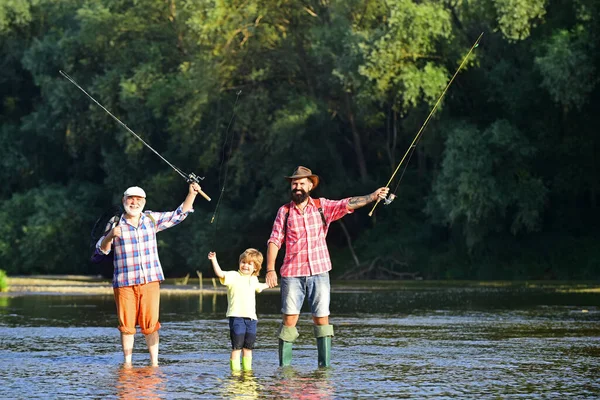 Papà e figlio pesca al lago. Pescatori familiari che pescano con mulinello. Nonno, padre e ragazzo pesca insieme. — Foto Stock