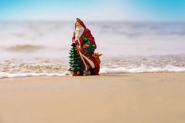 Toy summer Santa. Banner, poster or greeting cards. Christmas or New Year decoration on sea beach background with copy space. — Stock Photo, Image