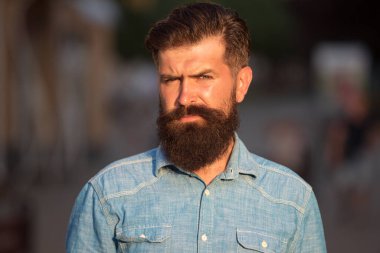 Sakallı yakışıklı hippi şehrin arka planında kameraya bakıyor..