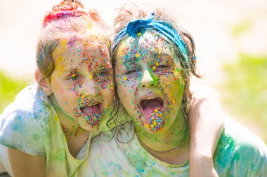 Mutlu bir çocukluk. Komik kız kardeşler, çocuk kızlar Hint bayramını renkli boya tozuyla kutluyor..