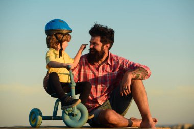 Loving family Father and son. Dad help his child boy ride a bicycle. clipart