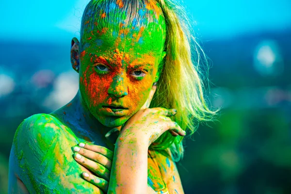 Цветное лицо с красочным всплеском палочки. Веселая молодая женщина с красочной краской на телах, развлекающаяся на фестивале в Холи. Холи - весенняя традиция индийского фестиваля цветов. — стоковое фото