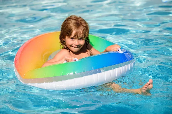Estilo de vida saudável das crianças. Bonito menino pequeno engraçado em um terno de natação colorido e óculos de sol relaxante com anel de brinquedo flutuando em uma piscina se divertindo durante as férias de verão em um resort tropical. — Fotografia de Stock