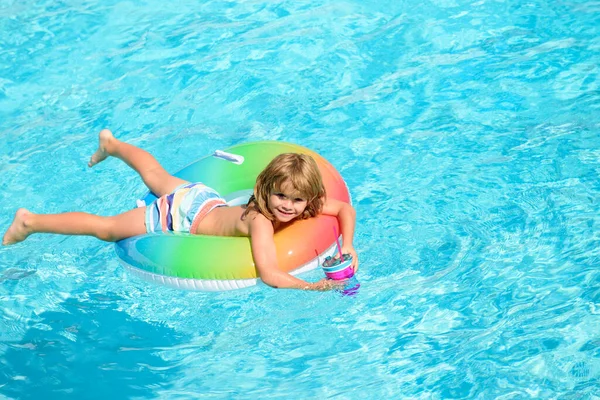 Leuke kleine peuter jongen in een kleurrijk zwempak en zonnebril ontspannen met speelgoed ring drijvend in een zwembad plezier hebben tijdens de zomervakantie in een tropisch resort. Grappige kinderen gezicht. — Stockfoto