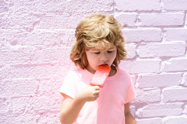 Το παιδί τρώει παγωτό. Χαρούμενο χαμογελαστό αγόρι που κρατάει παγωτό σε ροζ φόντο. — Φωτογραφία Αρχείου