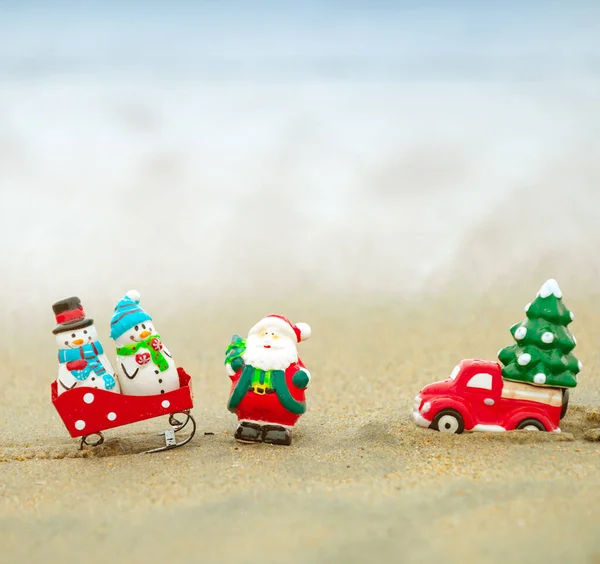 Spielzeug-Weihnachtsmann vor tropischem Ozean-Hintergrund. Weihnachten im heißen Urlaub. Warmes Neujahrsklima, Thema für Plakate, Grußkarten. — Stockfoto