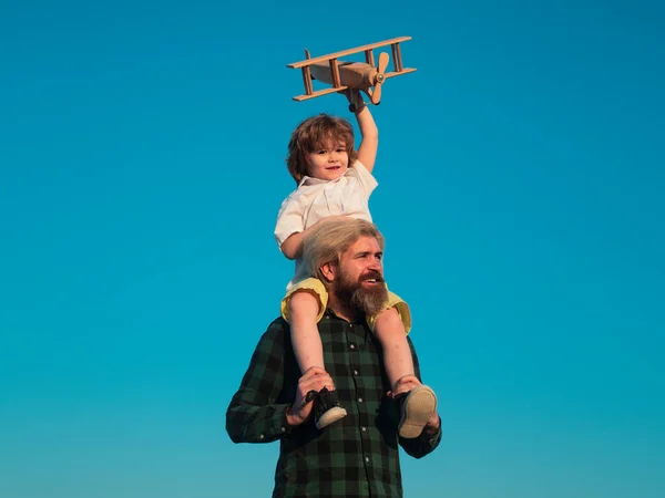 おもちゃの飛行機の男の子の父親の肩に座っている。飛行機旅行の夢を持つ幸せな父と息子. — ストック写真