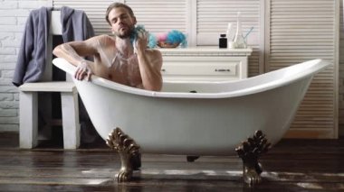 Banyoda tıraş makinesi olan kendine güvenen bir adam. Lüks tuvalette genç bir adam..