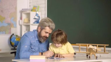 Baba oğluna öğretiyor. Babam çocuğuna matematik öğretiyor. Çocuk rakamlar yazıyor..