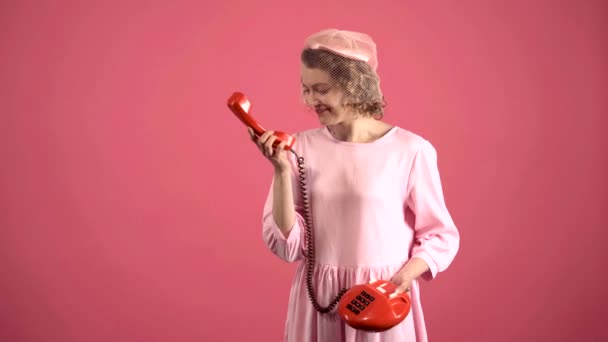 Lachende vrouw aan het praten op retro telefoon geïsoleerd op roze. Portret van een jonge knappe vrouw die aan het bellen is op Retro vintage telefoon. Pinup stijl. — Stockvideo