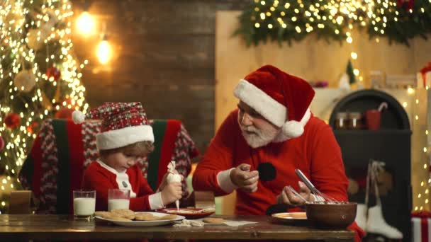 Papai Noel com criança ajudante assar biscoitos de Natal e preparar Natal ou Ano Novo. — Vídeo de Stock