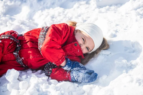 Flickan som ligger på snön. Roligt litet barn som har roligt i vinterparken under snöfall. — Stockfoto