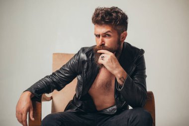 Seksi bir adam. Gece kulübünde şık bir modacı. Kendine güveni tam, odaklanmış, modern ceketli yakışıklı sakallı adam kanepeye oturur. Saygıdeğer erkeklerin güzelliği, modası. Genç hippi..