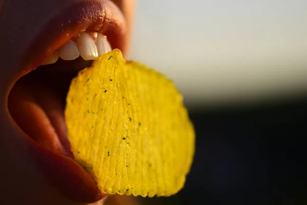 Sexy Frau Mund essen Kartoffelchips. Chips mit Zähnen, Zunge und Lippen schließen sich. Leckeres Fast Food. Chips essen. Fast Food. — Stockfoto