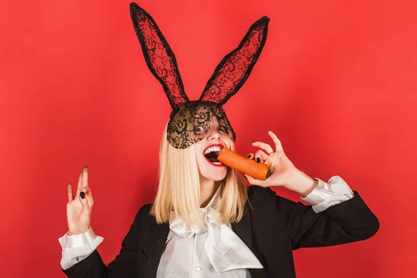 Osterfest. Sinnliche Frau mit schwarzen Hasenohren aus Spitze mit Karotte. Sexy Osterhase beim Karottenessen. Ostern ist ein Feiertag voller Spaß und Lebensfreude — Stockfoto