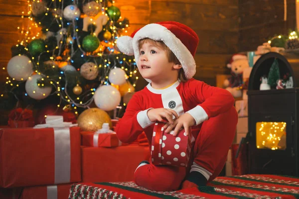 Joyeux enfant tenant une boîte-cadeau rouge avec les deux mains. Le matin avant Noël. Fête de Noël. Nouvel an Noël concept. — Photo