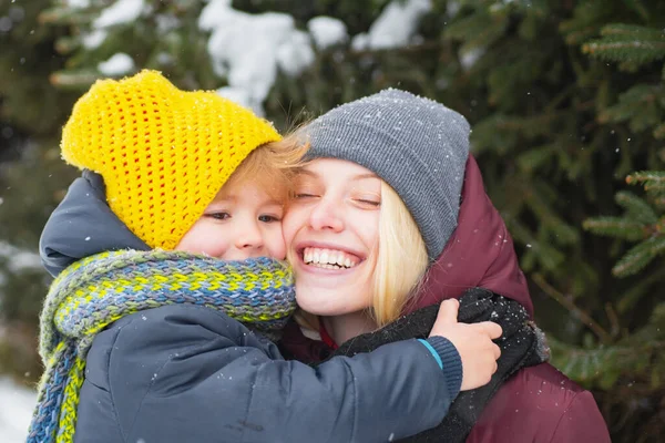 Kobieta z synem uśmiechnięta śnieżna zima tło natury. Święta i Nowy Rok. Mama i słodkie dziecko ciepłe szalik kapelusz. Zimowa koncepcja mody. Szczęśliwa dziewczyna bawiąca się z dzieckiem w zimowy dzień. Cieszący się zimą — Zdjęcie stockowe