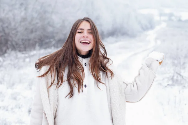 Glückliche Winterfrau auf schneebedecktem Hintergrund. Draußen. Fröhliche Schönheit junge Frau, die Spaß im Winterpark hat. Schnee im Winter. Winterliche Frauenkleidung. — Stockfoto