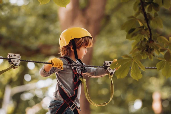 Glückliches Kind beim Klettern in den Bäumen. Aktivitäten für Kinder im Sommer. Frühkindliche Entwicklung. Kind. Sicheres Klettern Extremsport mit Helm. — Stockfoto