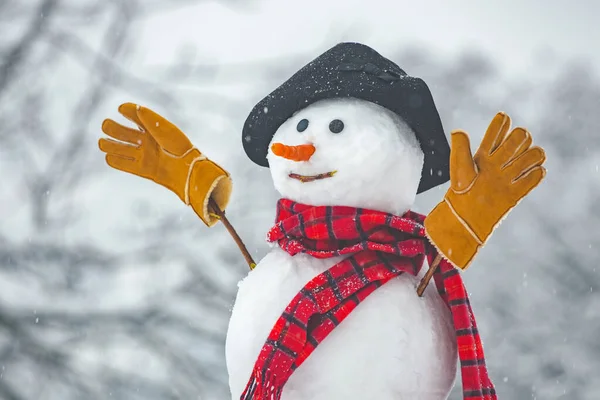 Happy funny snowman in the snow. Snow man in winter hat. Snowman outdoor. Funny snowmen. Cute snowman in hat and scarf on snowy field