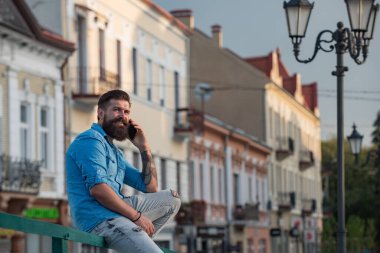 Dışarıda cep telefonuyla konuşan mutlu genç adam..