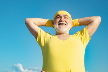 Özgürlük emekliliği kavramı. Mavi gökyüzü arka planında spor yapan yaşlı bir adam. Sağlıklı ve spor. Sağlık hizmetleri neşeli yaşam tarzı.