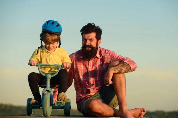 Glücklicher Papa hilft aufgeregtem Sohn beim Fahrradfahren. Vertrauen und Unterstützung. Das Gefühl der Unterstützung durch Eltern, Eltern. Vatertag. — Stockfoto