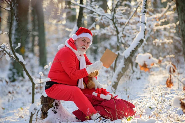 Jultomten läste julönskelista i snön skogen. — Stockfoto