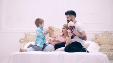 Çocuk ve ailesi yatağa uzanıp yumuşak oyuncaklarla oynuyorlar. Mutlu bir aile, baba ve oğul kavramı. Mutlu aile yatakta iletişim kurar..