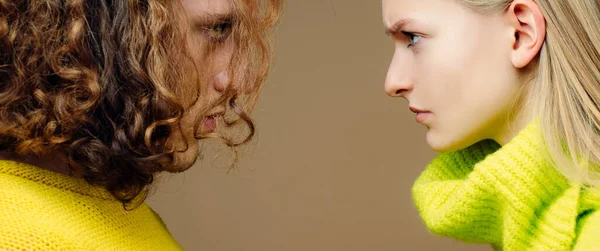 Foto de cerca de dos jóvenes personas serias y confiadas de pie cara a cara entre sí. Pareja joven discutiendo sobre el fondo del color. Problemas de relación. —  Fotos de Stock