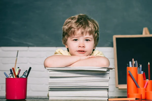 Otthoni vagy iskolai oktatás. Portré gyerek az általános iskolából. Egy kölyök egy könyvvel. Chalkboard másolási hely. Aranyos gyerek fiú az osztályteremben, közel a táblához.. — Stock Fotó
